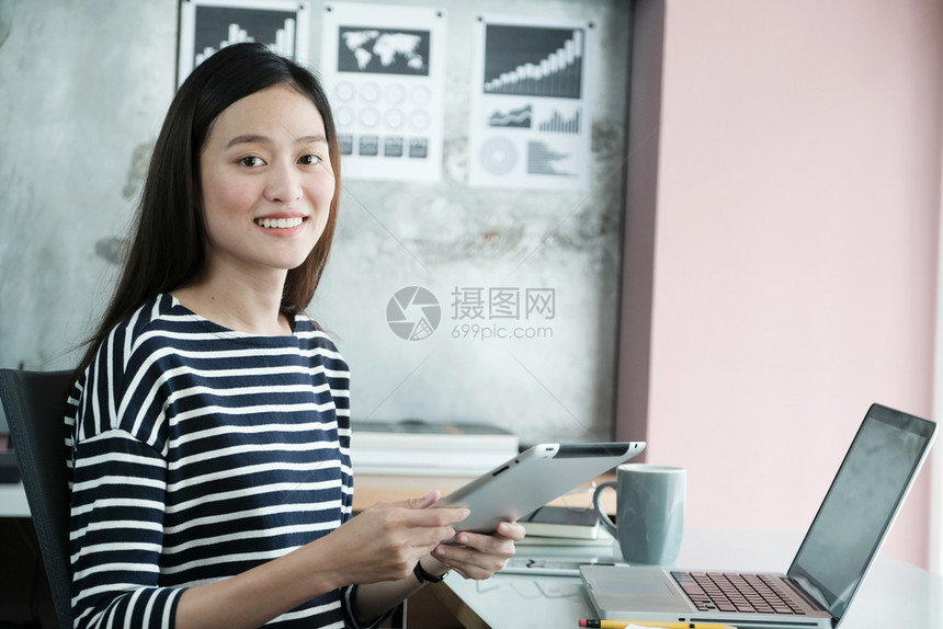 情感年轻的亚洲女商人在办公室临时生活概念中使用有微笑脸的平板正面情绪和积极的平板在职亚洲人图片