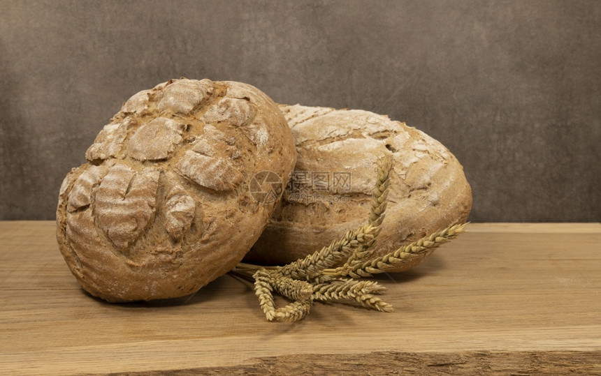 木制架上两块新鲜烤面包木制板上两块面包美味的食物棕色图片