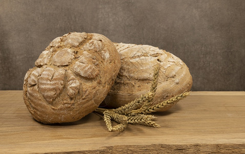 木制架上两块新鲜烤面包木制板上两块面包美味的食物棕色图片