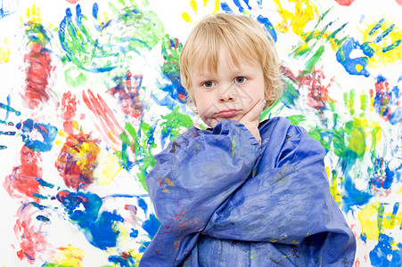 吃饱的男孩艺术家印刷一个年轻男孩画了一幅色彩多的指膏画后看着温柔和满足围裙背景