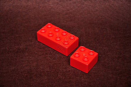娱乐棕色背景的两个不同大小红色建筑块塑料物图片