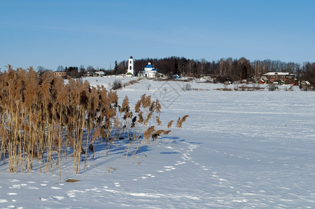 晴天冬季农村风景阳光明媚的天气是寒冷河流和岸边干草冷冻钟图片