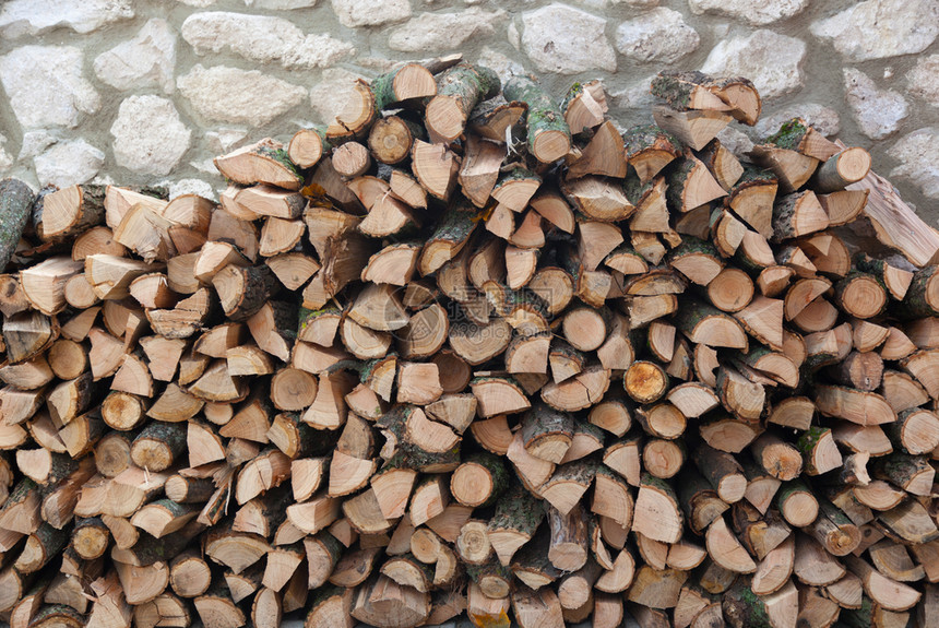 桩堆叠的木制石墙壁上木柴背景和纹理图片
