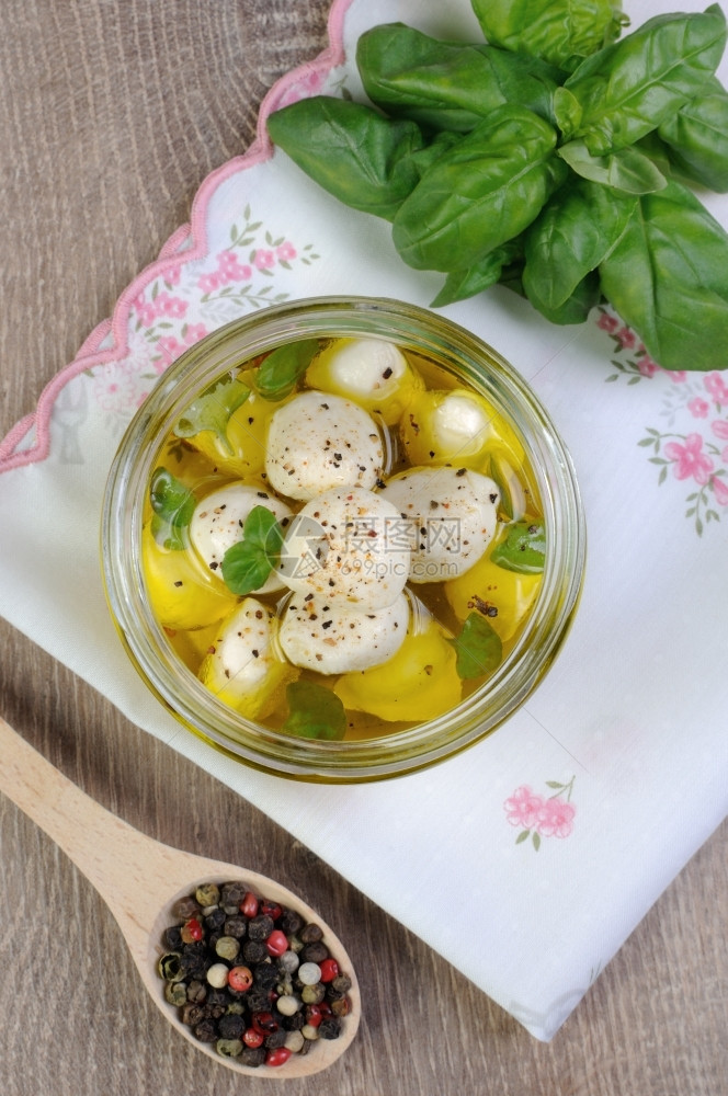 奶酪橄榄油中的婴儿马扎里拉和玻璃罐的草药食物茶点图片