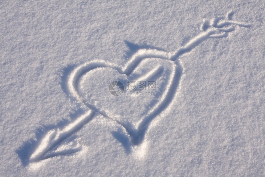 冬天户外箭穿透雪上的心脏爱图片