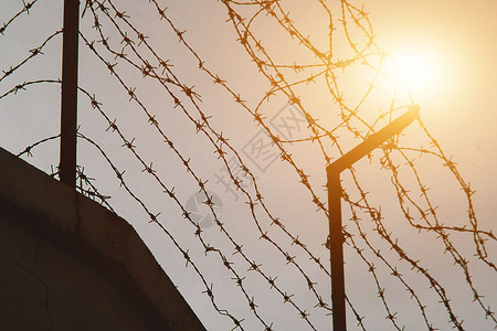和平倒钩金属钢铁丝网墙和阳光作为希望自由监狱和希望的概念图片