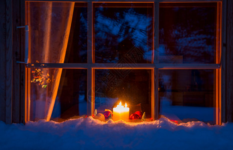 礼物木制的家屋雪夜窗在台上是圣诞装饰品和燃烧的蜡烛雪木窗圣诞装饰和蜡烛背景图片