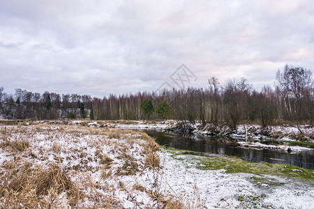 一种颜色第场白雪落在秋天的阴云落到小河岸上的黄干草地景观图片