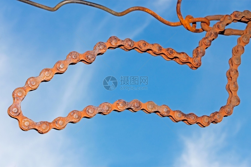 技术的双环旧生锈钢链挂在对蓝天的铁丝网上曲线图片