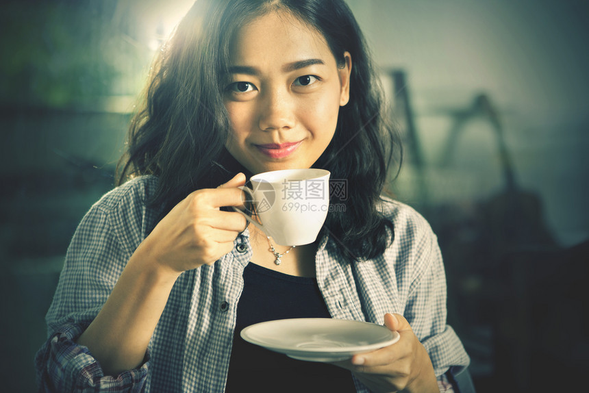美丽在白杯中喝热咖啡的亚洲年轻女脸看图片