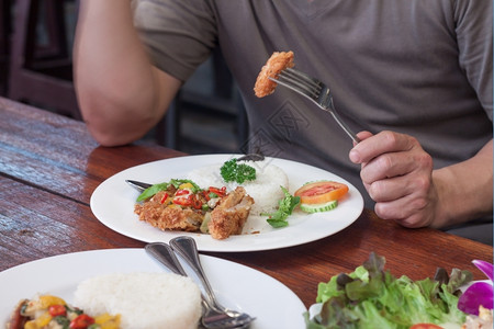 油炸男人吃鸡翅和茉米饭在白盘餐时间美味的泰国图片