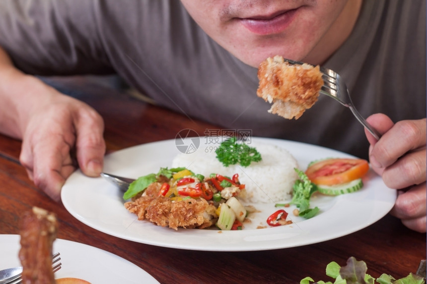 男人吃炸鸡翅和茉米饭在白盘餐时间美食亚洲泰国图片