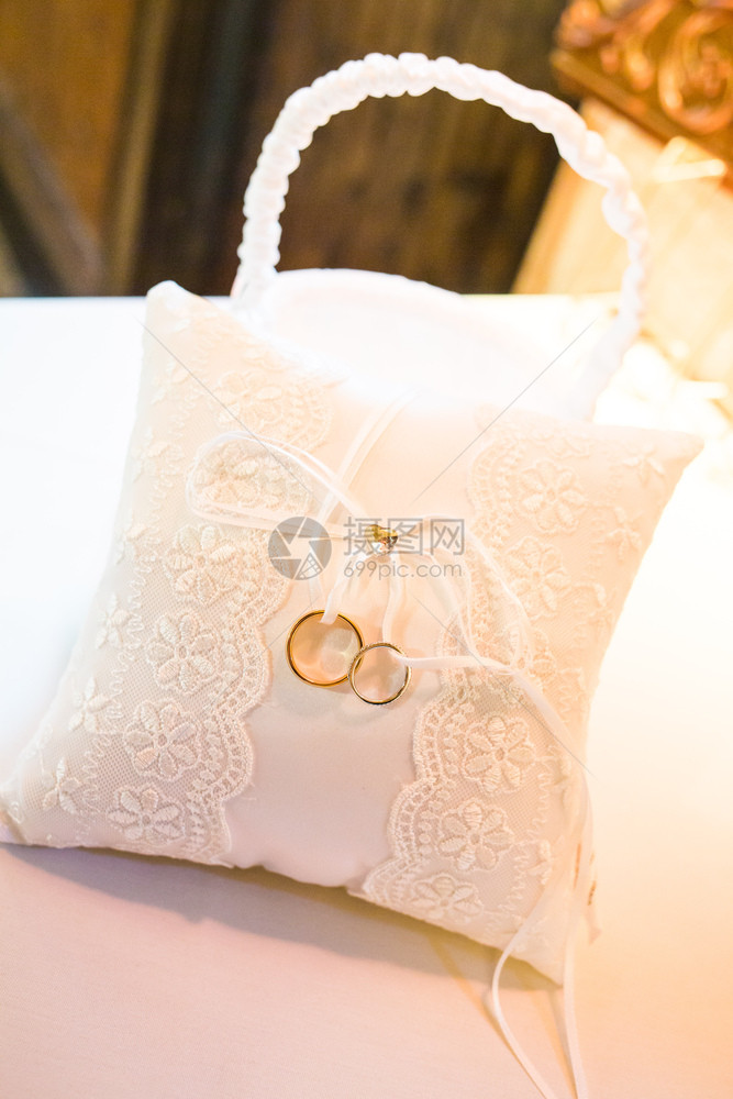 白色枕头上的两个金婚戒特写白色枕头上的两个结婚戒指特写金的象征爱图片
