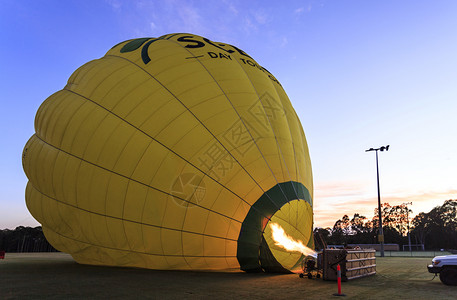 黄色热气球燃气热球因烧丙烷体而膨胀在澳大利亚昆斯拉姆德的黄金海岸上空日出飞行膨胀的经过燃烧器背景