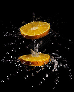 黑色背景上孤立的多汁橙色切片旋转和泼水的创造构成图象林茶点饮食图片