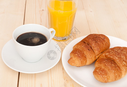 新鲜的卷早餐面包咖啡和木制餐桌上的橙汁子图片