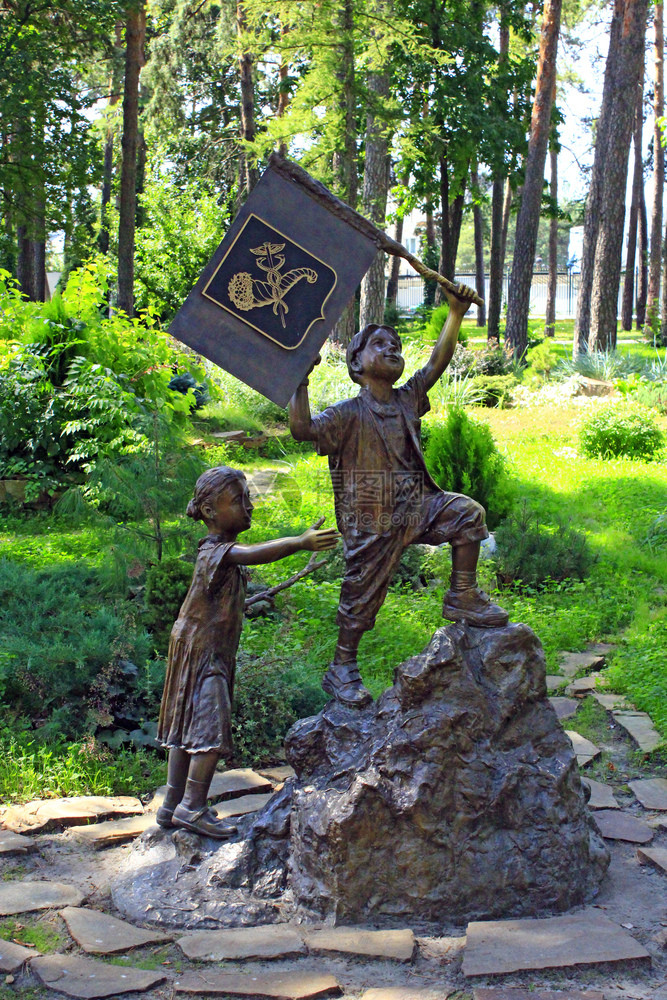 男生建筑人类带着和女孩上山在城市公园纪念碑中向哈尔基夫市公园的儿童赠送有和女孩上山在城市公园中的男孩青铜雕像与悬挂和女孩上山图片