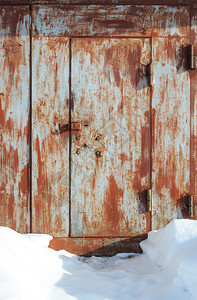 户外关闭了老旧的生锈金属车库大门雪中狭窄的步行道腐蚀弄脏图片