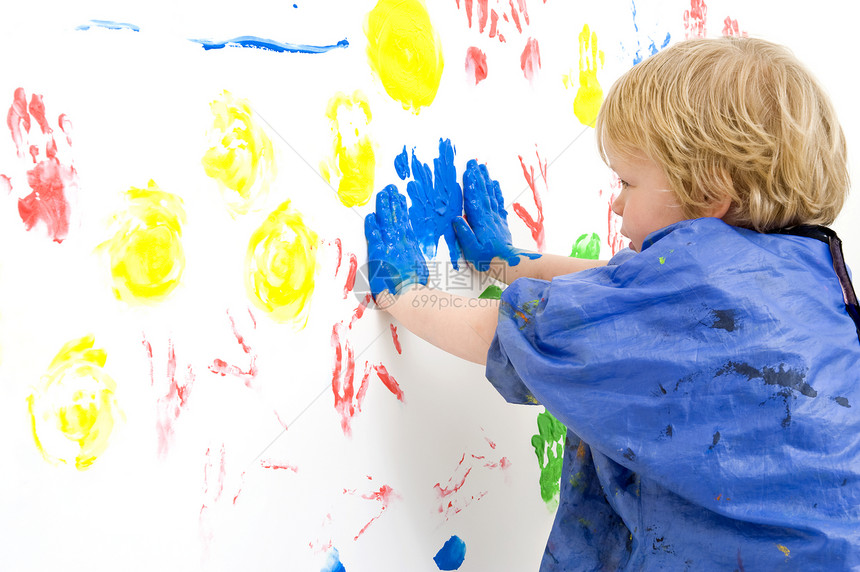 一个年轻男孩用手按住他的全身涂满蓝颜料靠墙对着用手指涂漆印刷纹玩围裙涂抹图片
