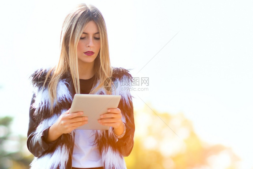 药片技术青黄色的年轻女子在街上看平板牌道图片