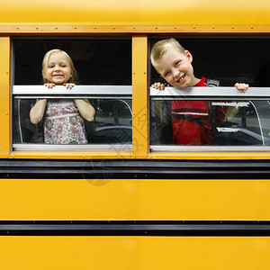 照片中两位快乐的孩子们向黄校车窗外看风的照片充满文字空间初级教育学校图片
