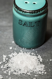 食物矿盐沙摇晃器和石黑桌上的研磨盐在陶瓷摇晃器周围切除白盐结石图片