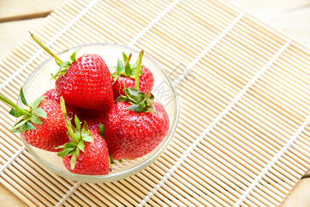 甜点竹子背景的碗里新鲜草莓浆果有机的图片