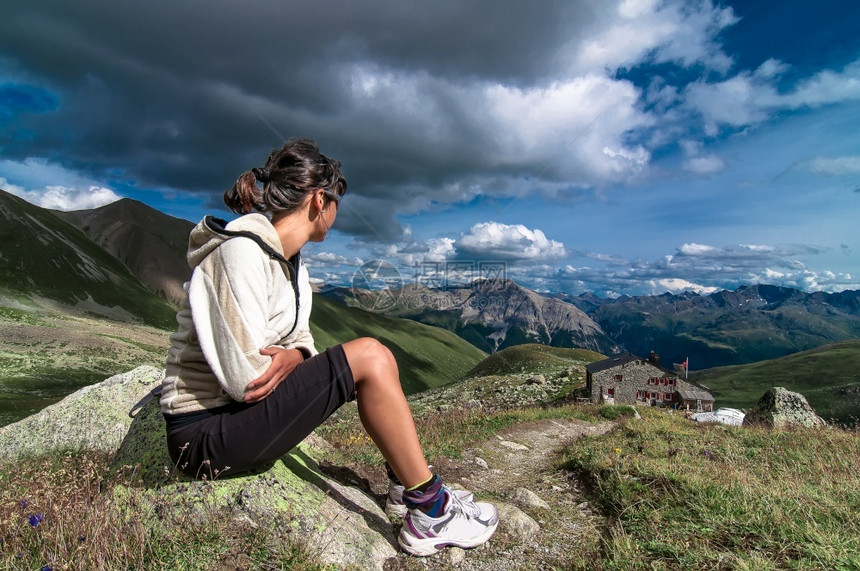 自然坐在山上的女人看到一个高山小屋和夏天的风景孤独滑雪图片