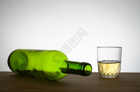 舍纳塔根玻璃灰色的酒精绿葡萄瓶和木制桌上的白酒杯设计图片