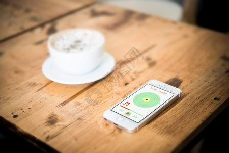 手机音乐播放界面界面移动的与音乐播放器智能手机在屏幕上播放Wooden案桌和咖啡厅抽象的背景