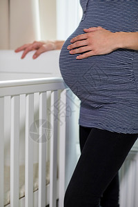 保持肚子人们紧贴孕妇触摸胃的近身站立在护士室的Cot旁边图片