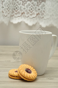 美味的白杯加咖啡和圆果酱的白杯子填满了饼干吃甜的图片