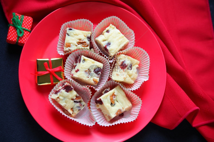 喜庆的家蔓越莓用白巧克力红纸巾和小礼物制成的圣诞果酱配有白巧克力红莓和核桃以及餐巾和微型礼品图片
