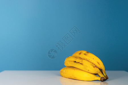 饮食或者黄色的白桌前蓝墙面的白桌上成熟黄香蕉的前视线白天健康有机素食或品水果背景图片