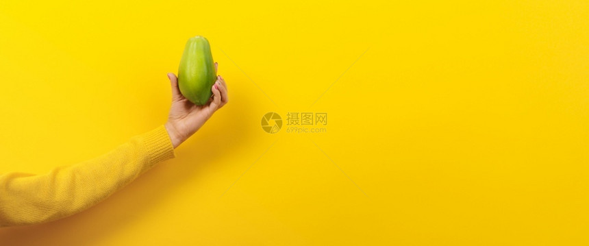 甜点女士持有黄色背景绿木瓜健康食品概念带文字空间的全景图像妇女手持绿色木瓜生的图片