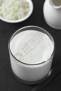 菲尔尔Kefir杯中新鲜自制的Kefir饮料背面有kefir粒子和牛奶与自然光选择焦点拍照在基菲尔饮料中聚焦三分之一以数字变换不饱和图背景