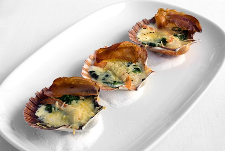 营养新鲜的起司贝壳中塔斯马尼亚扇贝与潘塞塔菠菜和两奶酪酱一起烤图片