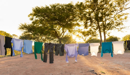 新鲜的服装明亮男人和女在户外衣干线上洗服后面有钉子和太阳流进来图片