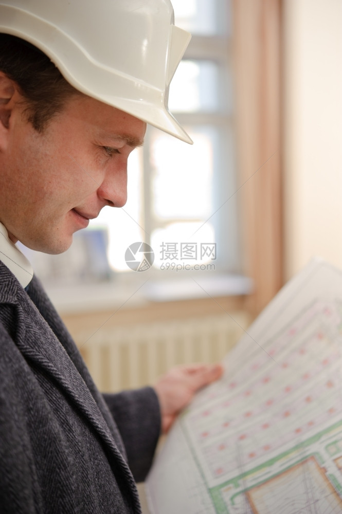 男人在职的工程师或建筑设计的硬帽子看计划商业图片