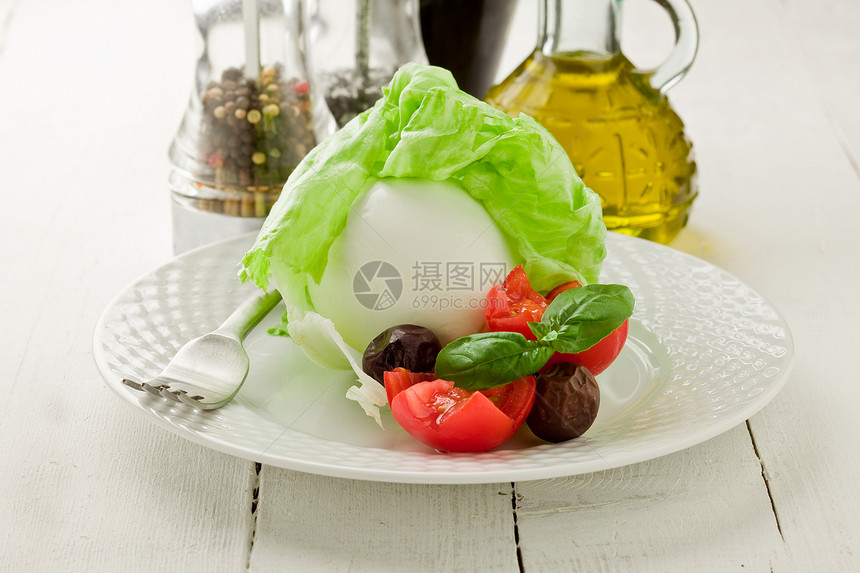 香脂沙拉美味的水牛马zzarella配有包装生菜和木制桌上的西红柿醋图片