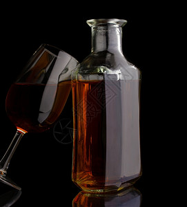 反射白兰地瓶和玻璃在黑色上隔绝白的酒精图片