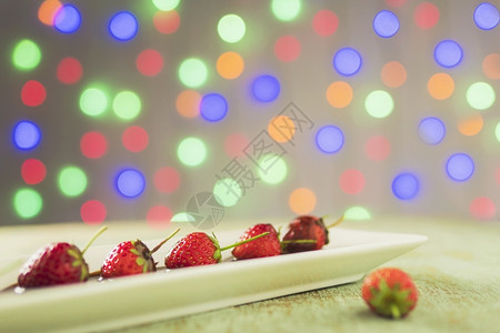 斯林拉特木制的美丽白色盘子里有巧克力大衣的草莓超过多彩光浅布基背景图片