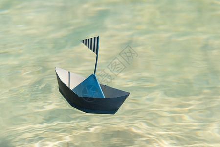 脆弱海浪在水上漂浮的蓝纸船图片
