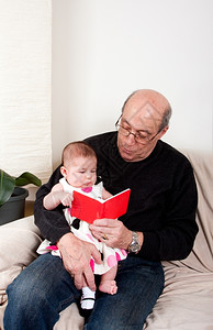 女长椅教学快乐的祖父读了一本小红书给个女婴儿坐在父亲腿上同时被教育阅读坐在厕所的沙发上背景图片