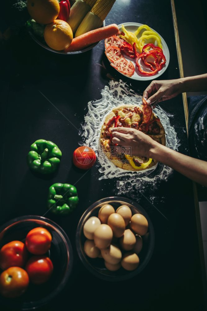 酱女人的顶端视角在自制披萨上涂点油美味的小吃图片