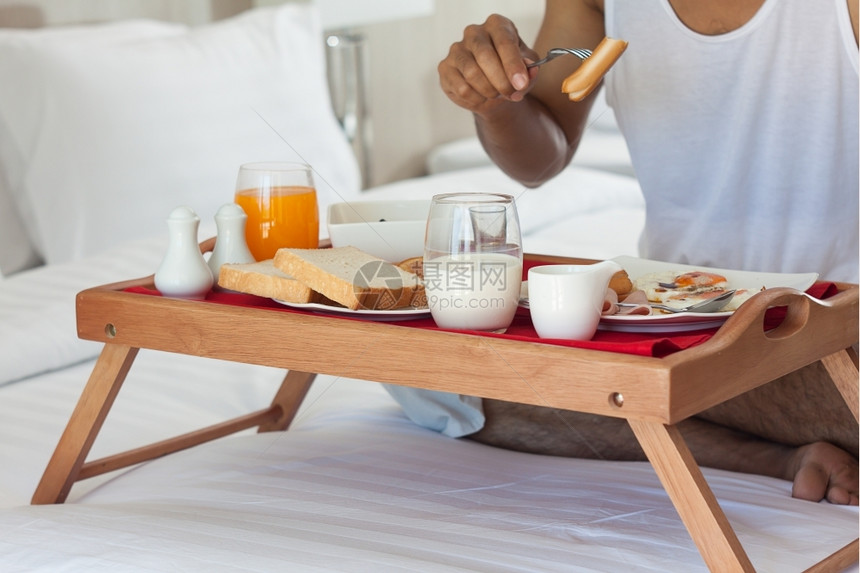 早晨男人在床上餐盘吃早果汁香肠图片