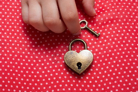 手握着心脏形状的锁和红色背景钥匙抓住二月一种图片