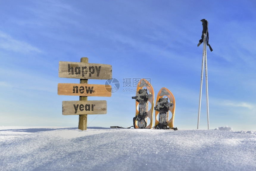戳白色的下一个雪鞋和滑板木棍牌雪鞋和滑棍旁边的地上新年文字快乐雪花鞋和滑棍图片
