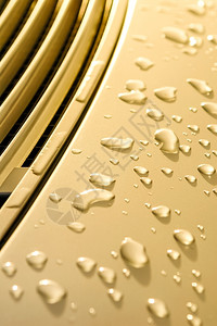 降低金色涂漆上有雨滴的车面图板闪发光湿的图片
