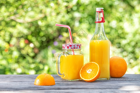 饮料一种果汁和橙子在木制桌上绿色天然背景夏生还的瓶子和罐在木制桌上加橙汁和橘酒玻璃背景图片